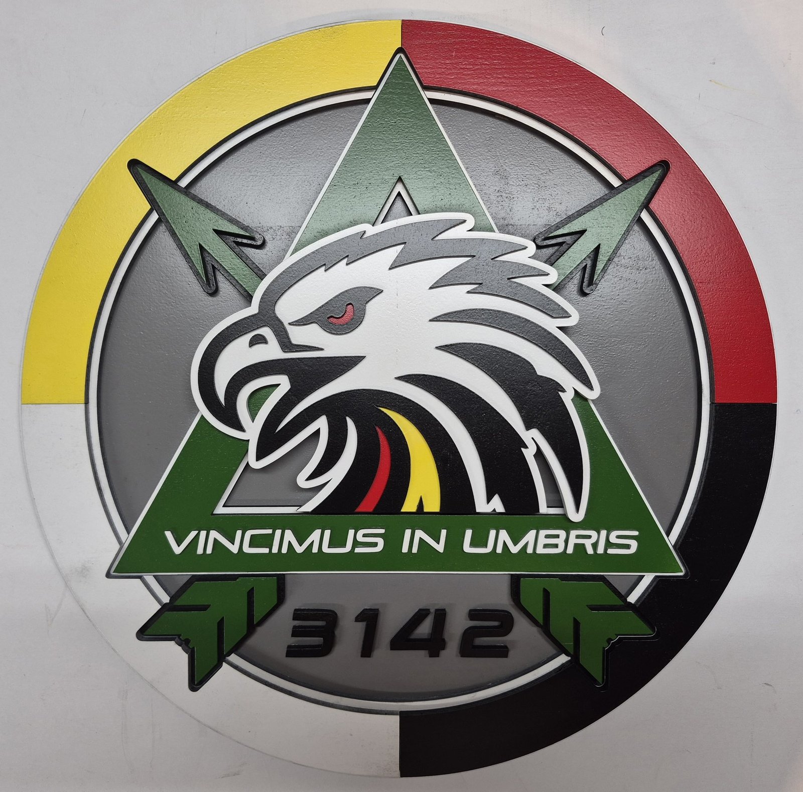 Round military unit plaque with an eagle head, green arrows and a multicolored border.