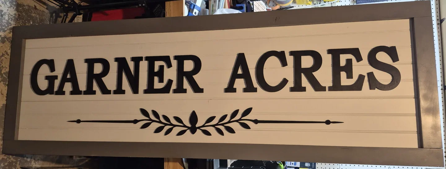 Rectangular Garner Acres farmhouse sign with dark raised lettering on a light wood background.