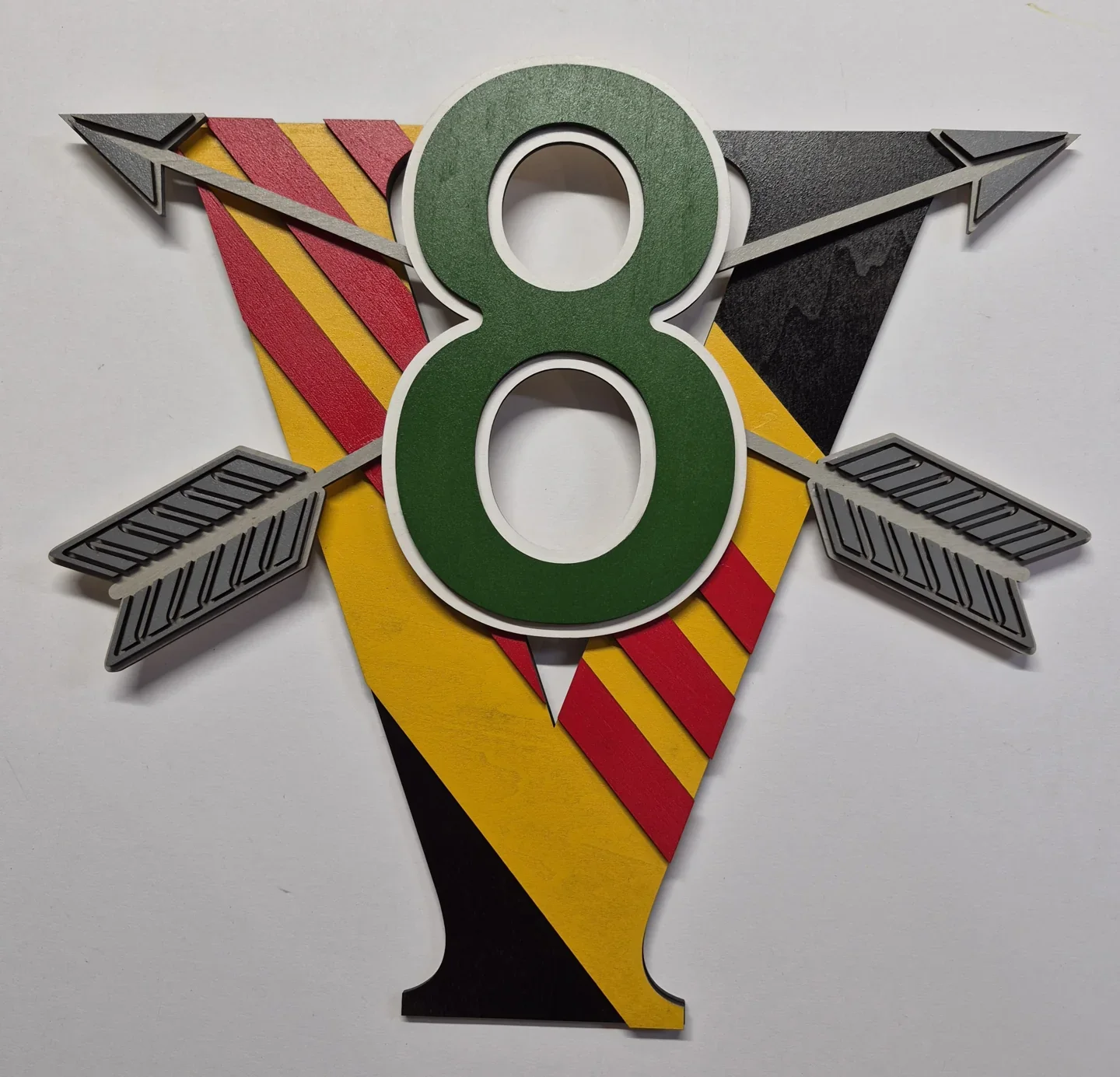 Multicolored number eight military emblem with crossed arrows and layered details.