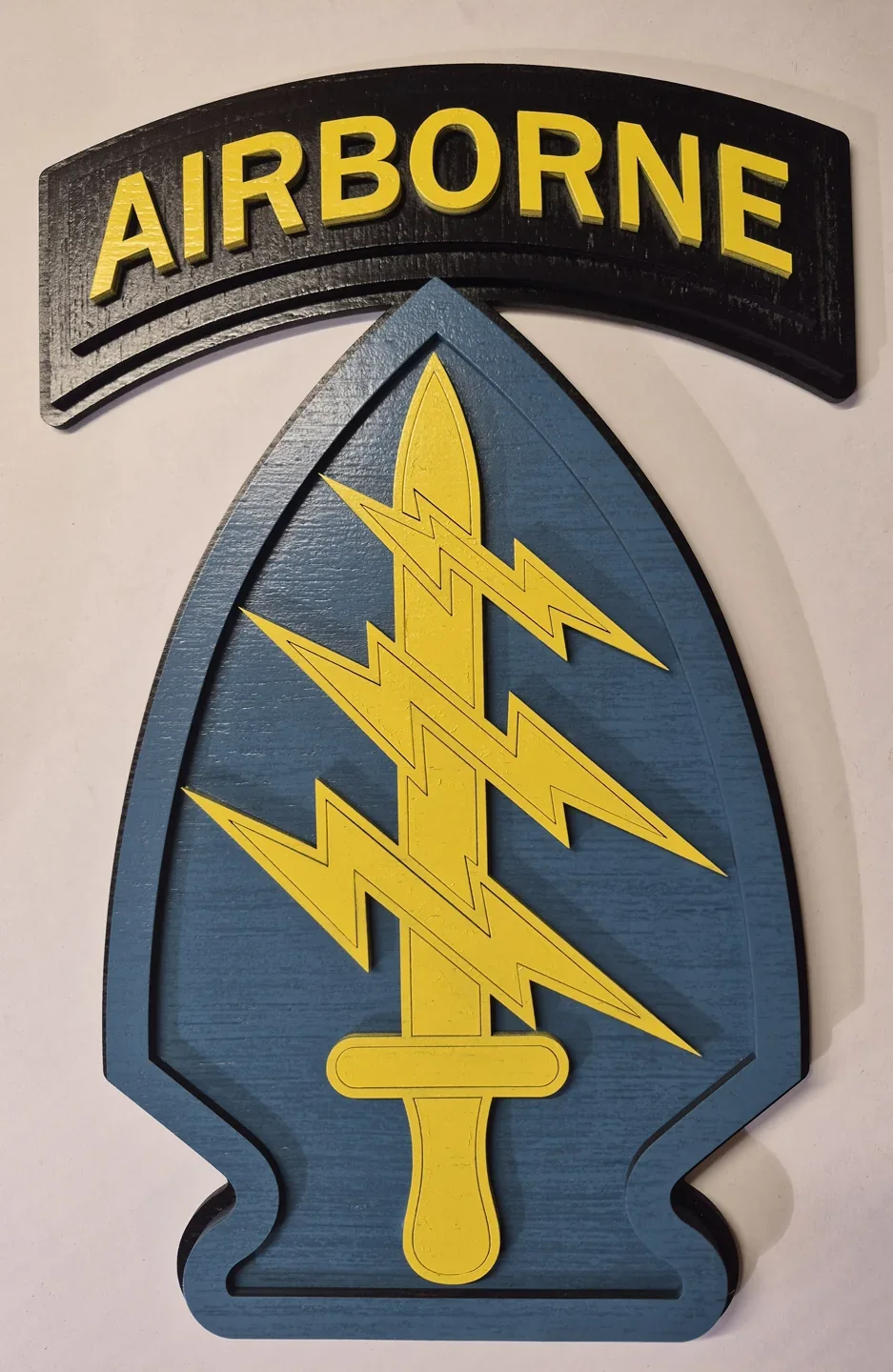 Airborne lightning insignia with yellow bolts on a blue spearhead below a black and yellow tab.
