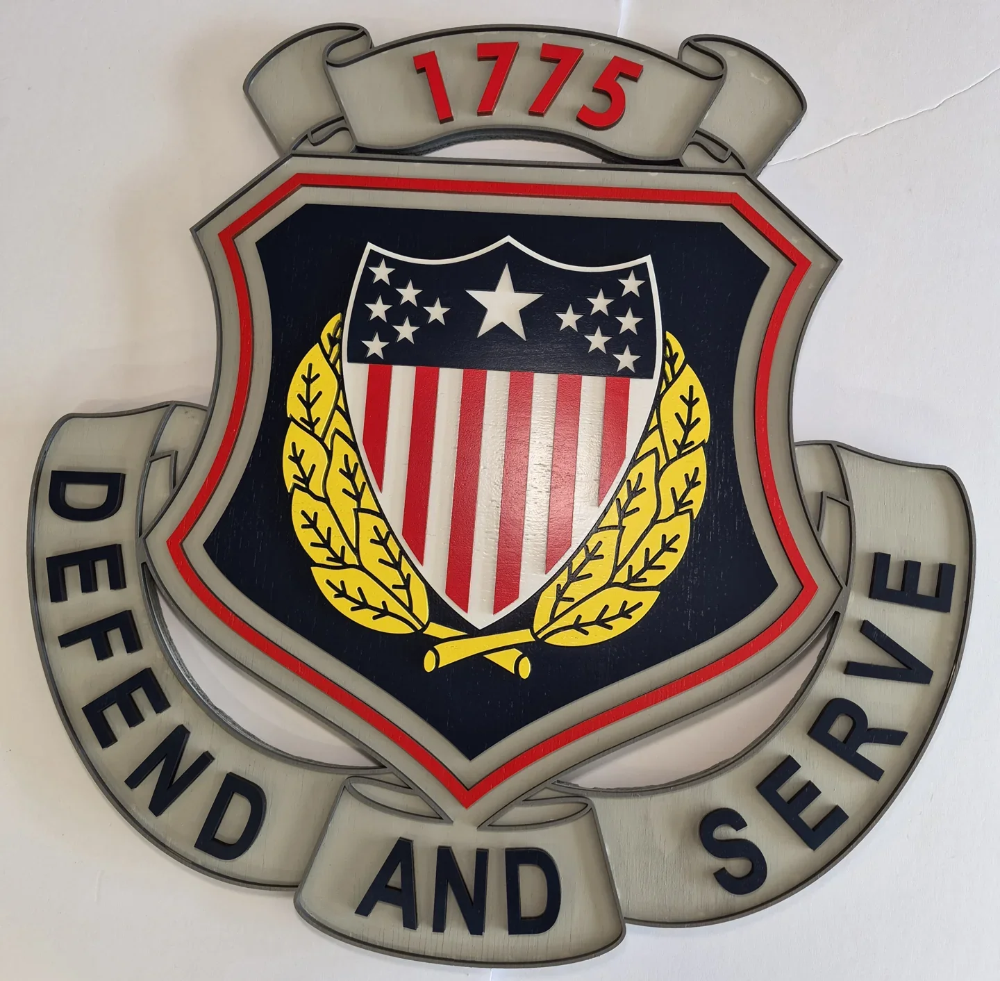 Defend and Serve shield with a flag, crossed axes and raised lettering.