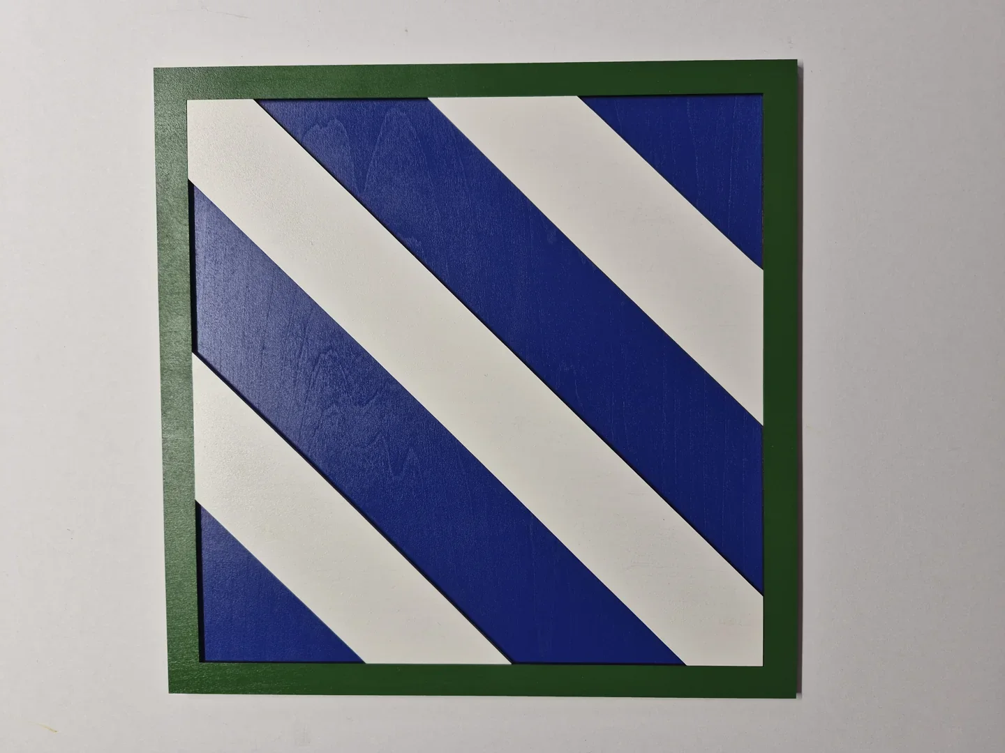 Blue and white diagonal stripe unit shield with a green border.