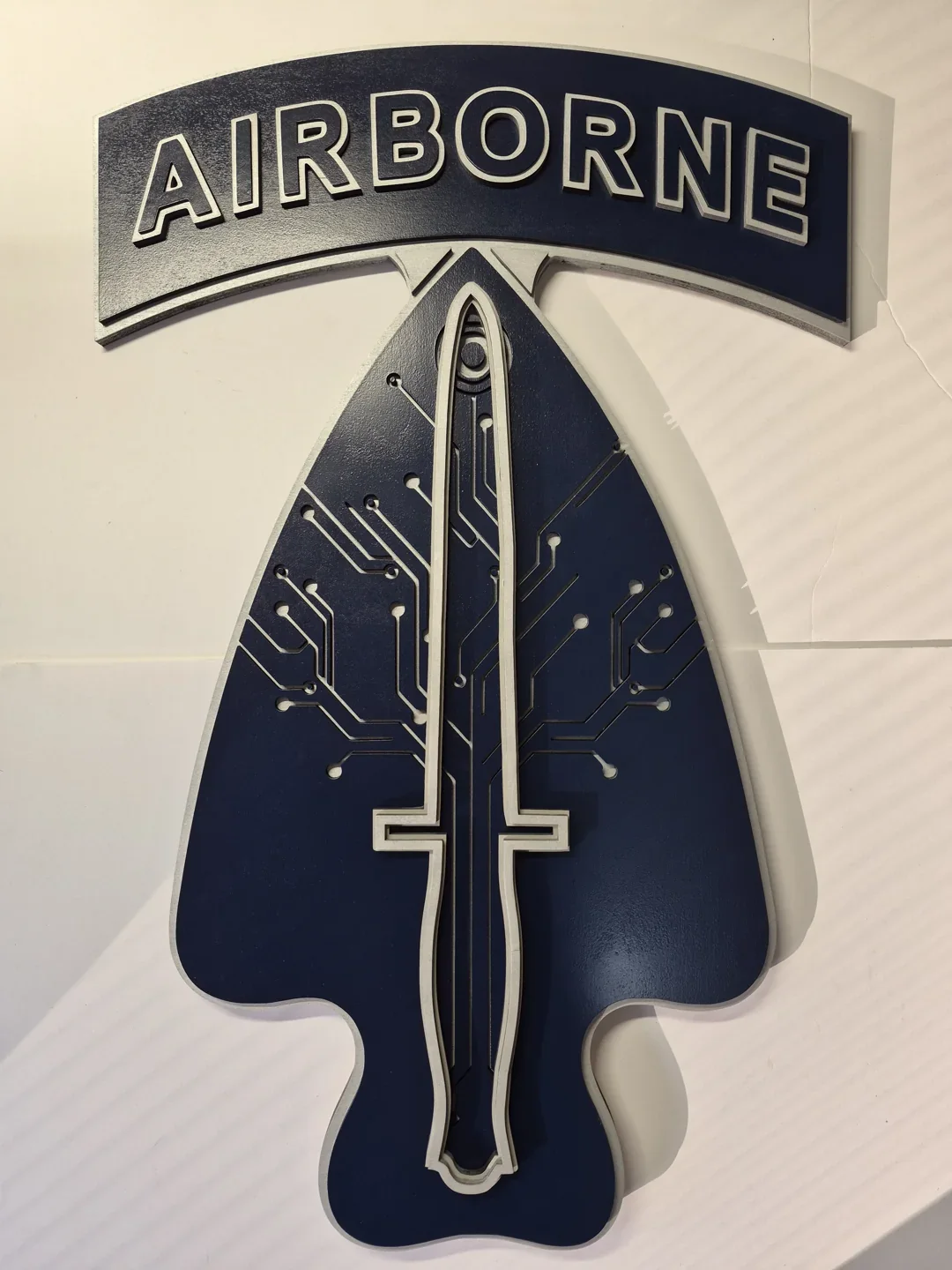 Airborne spearhead plaque with a dark central blade and a curved matching tab.