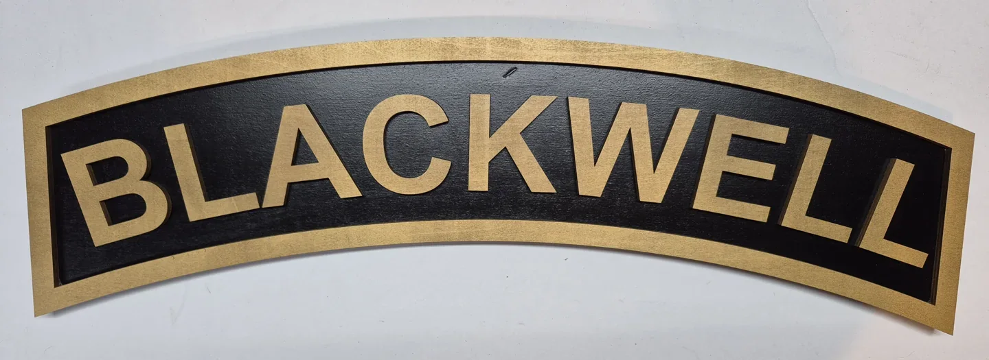 Blackwell personalized name scroll with gold lettering and a curved black background.
