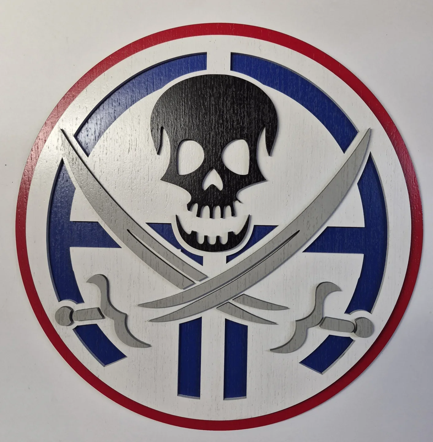 Round red, white and blue skull plaque with crossed blades.
