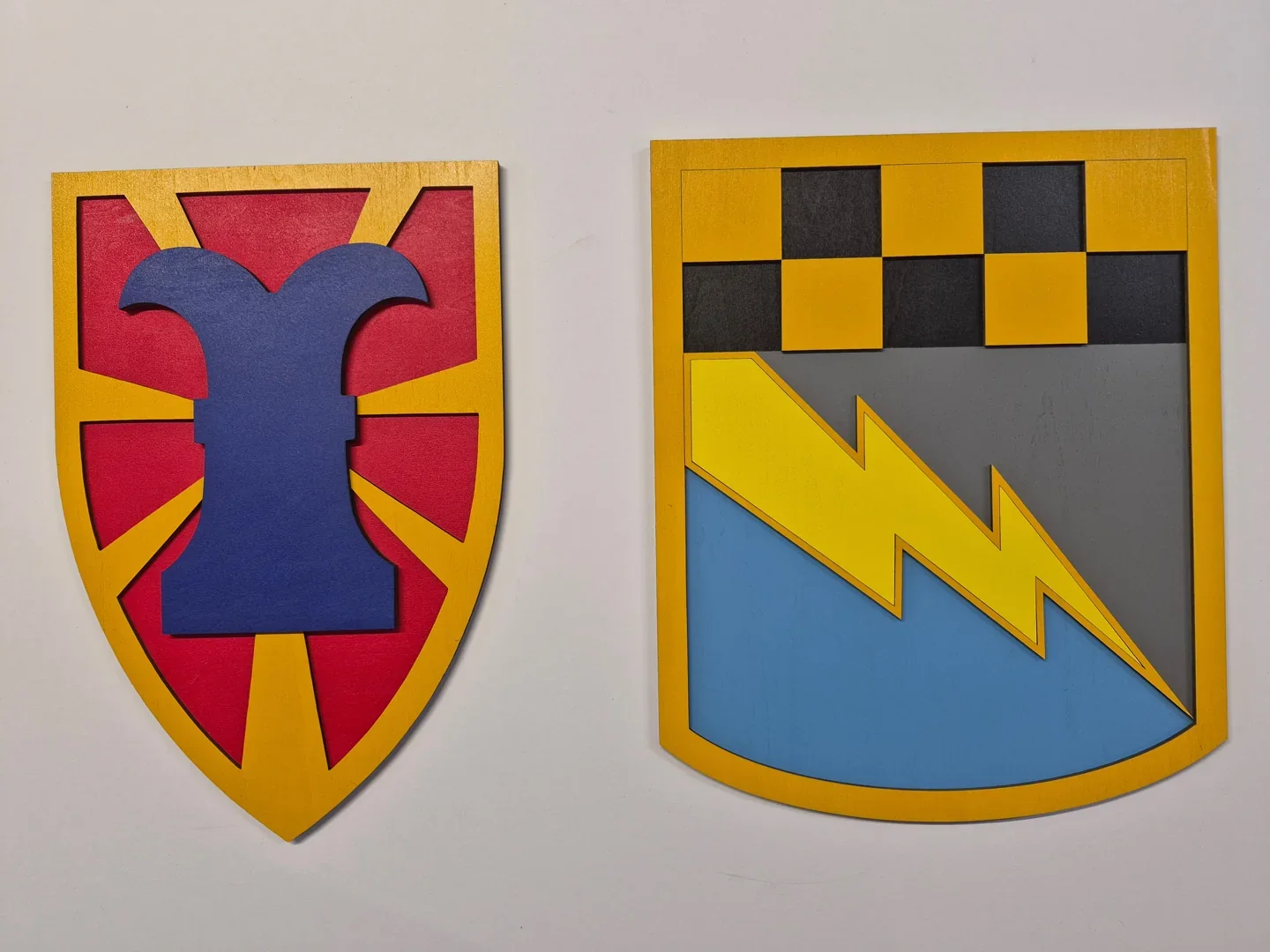 Pair of colorful unit insignia with a goblet silhouette and yellow lightning bolts.